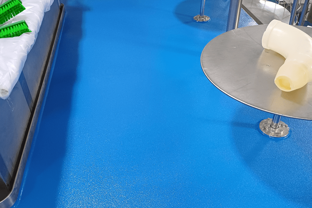 Blue industrial floor with table and brushes.