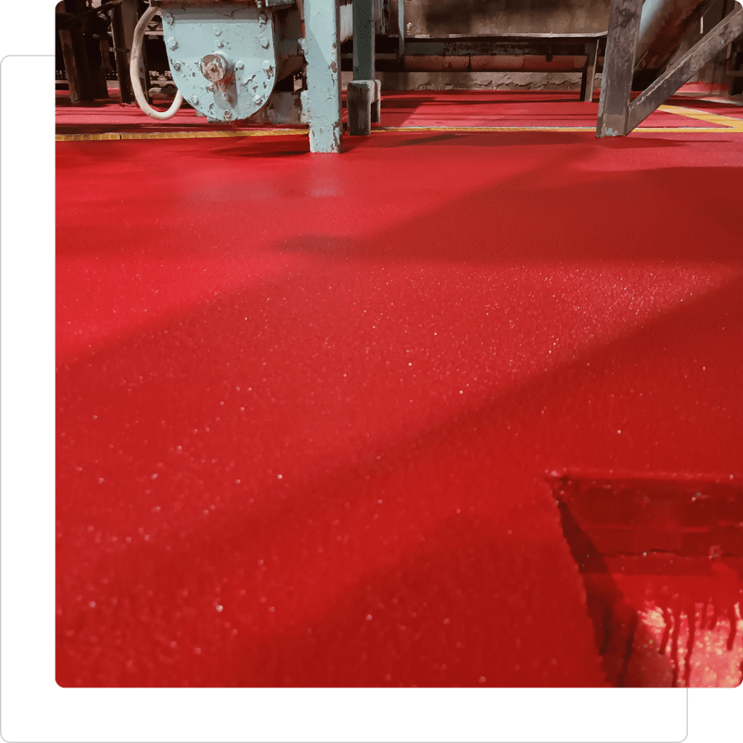 Red industrial floor with machinery above.